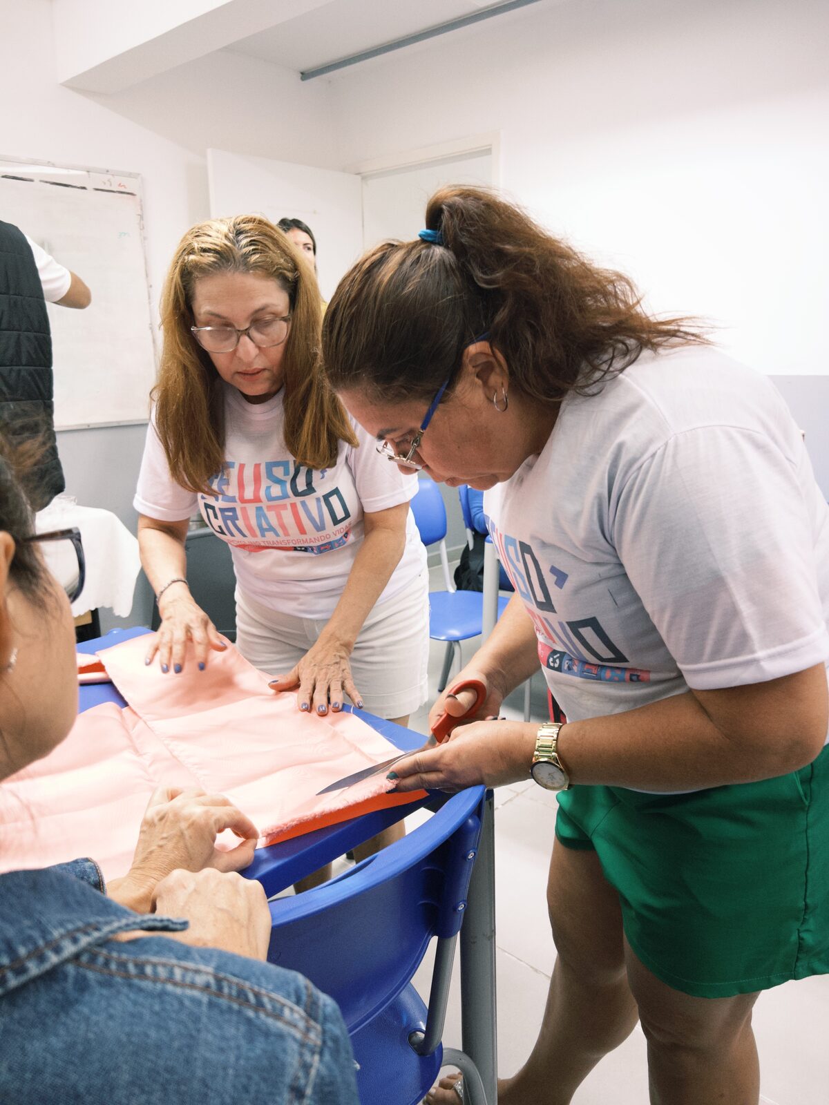 Alunas orientadas durante o corte de tecido em uma aula prática